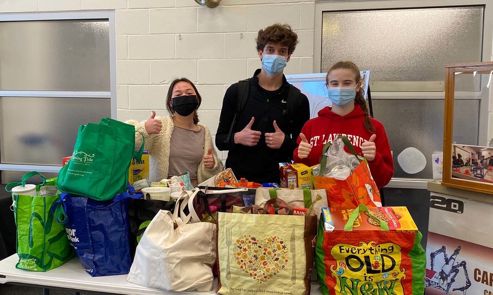 Students behind table with 200 pounds of food in bags